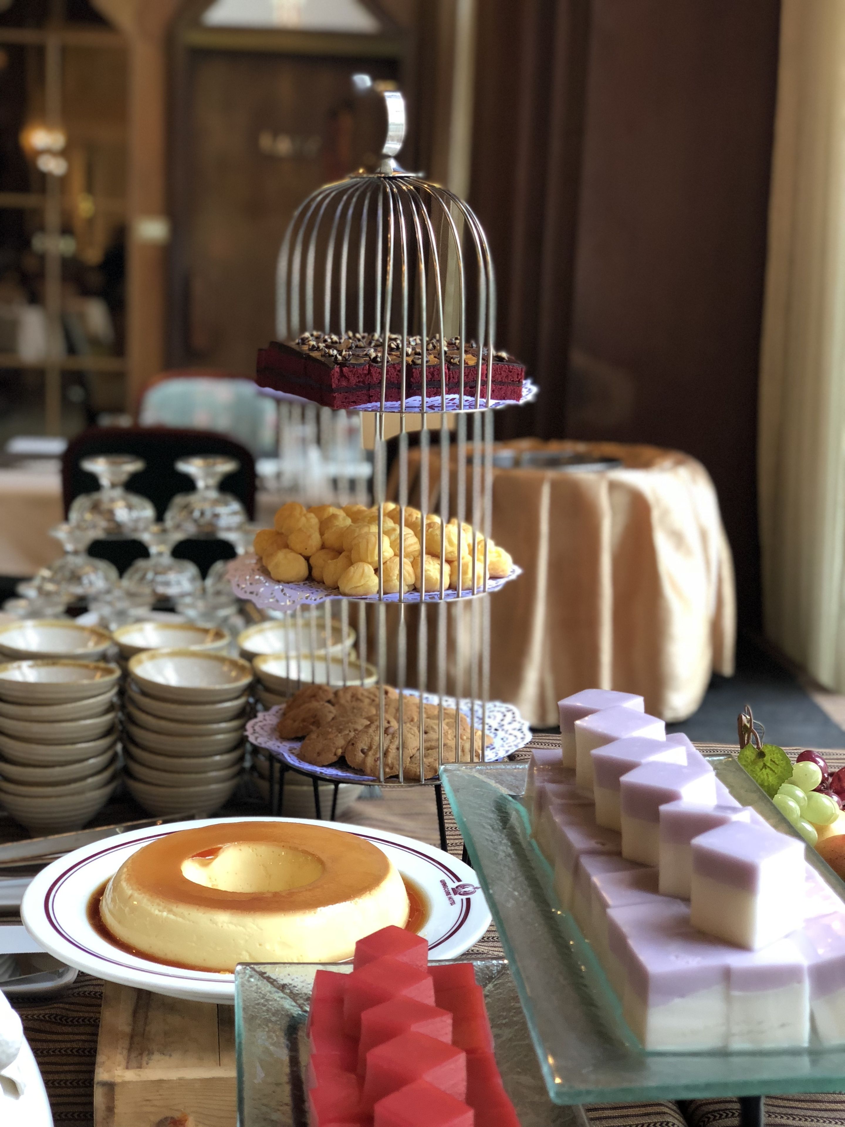 A dessert buffet with various cakes, cookies, and pastries displayed on tiered stands and plates.