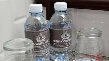 Two water bottles with labels on a granite countertop near a window with a wooden frame.