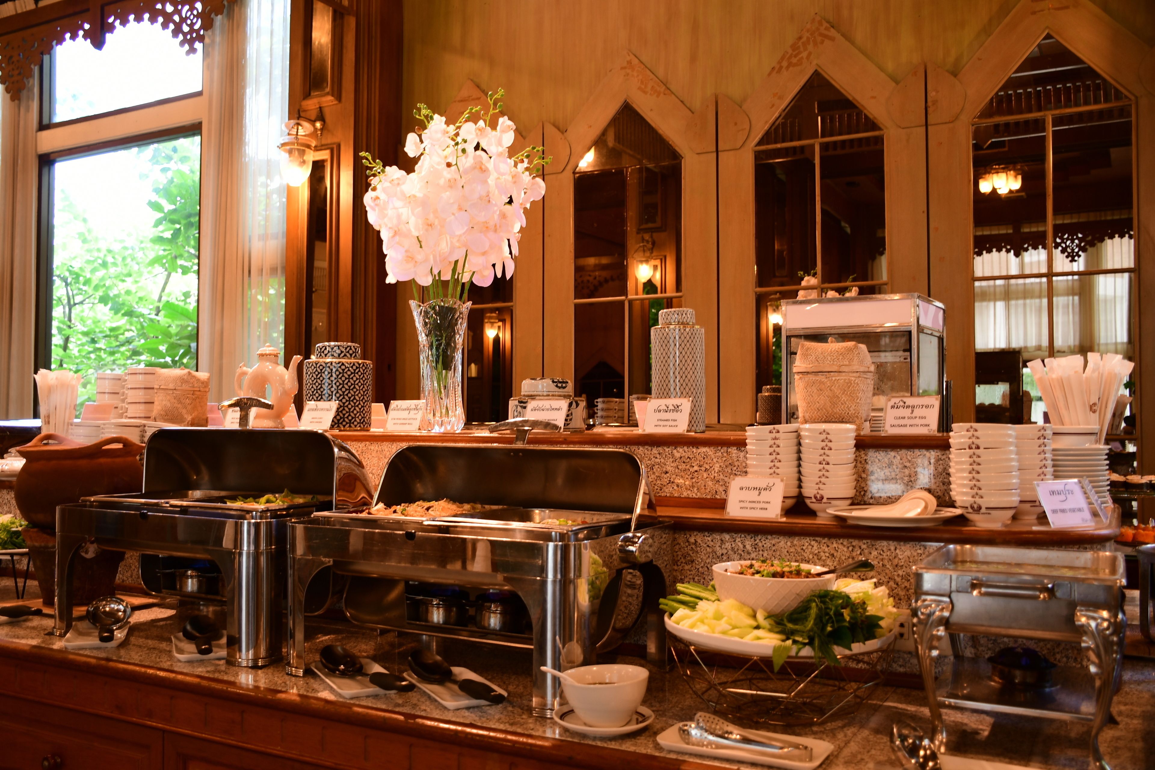 Un buffet avec différents stands de nourriture, une machine à café et un vase décoratif rempli de fleurs.