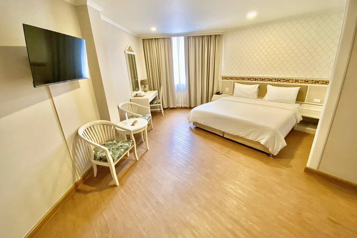 A hotel room with a bed, a desk, a chair, and a television.