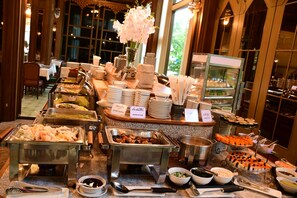 A buffet setup with various food items and utensils. - Wangcome Hotel (Chiang Rai)