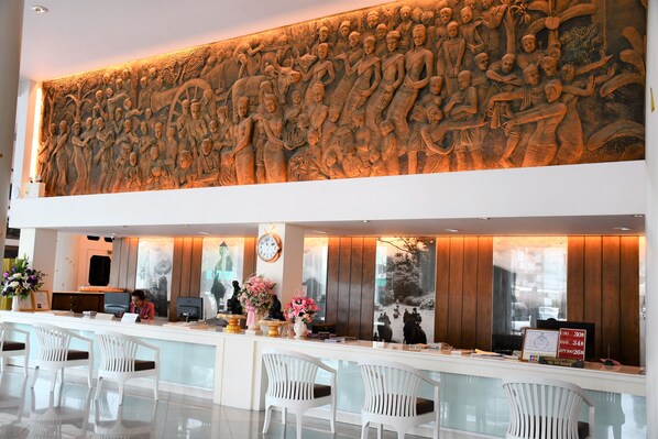 A reception area with a large wall mural, a reception desk, white chairs, and a clock.