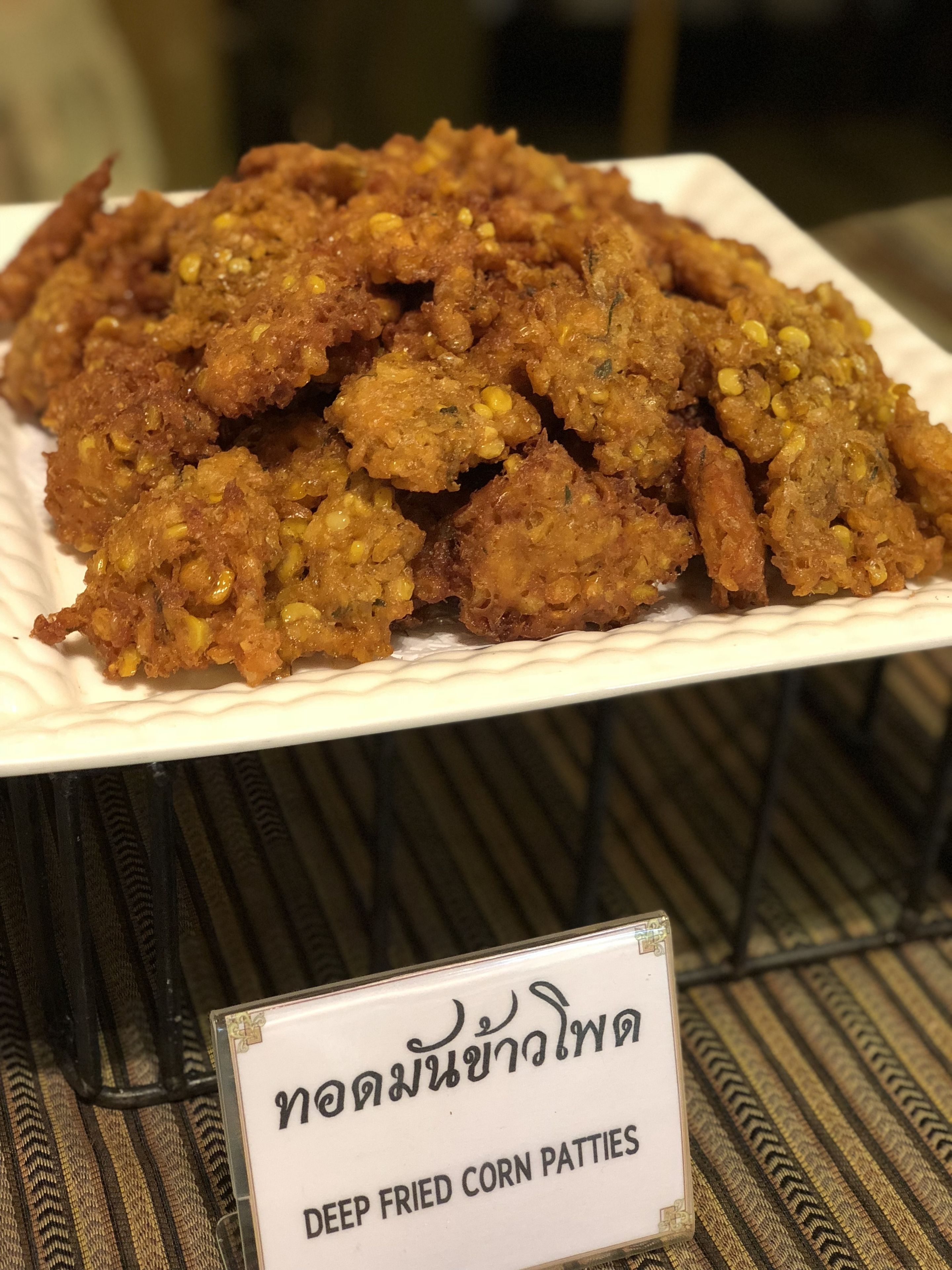 A plate of deep fried corn patties with a sign in a foreign language.