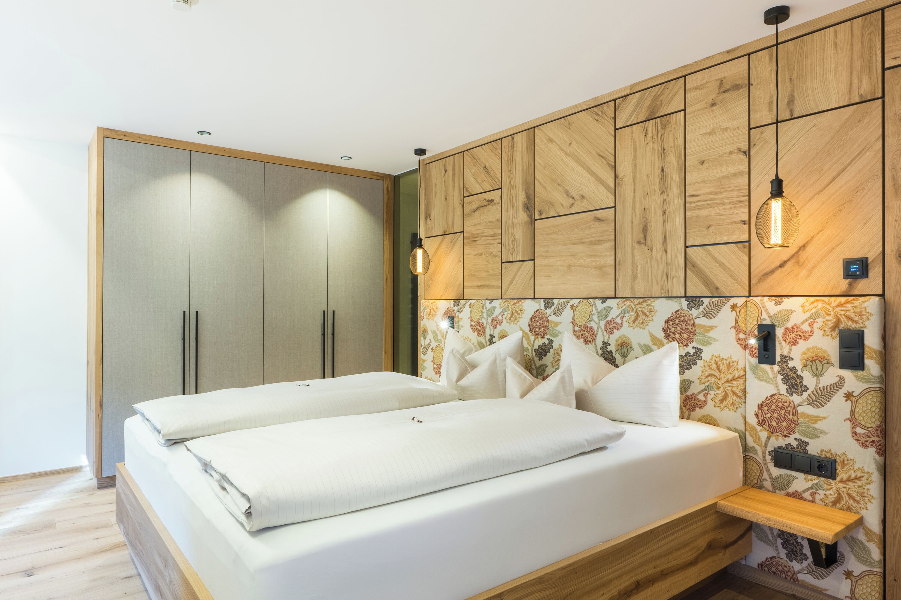 Ein Schlafzimmer mit einem Bett, einem Holfischschrank und einem Kopfende mit Blumenmuster.