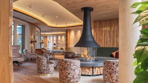 Un interior moderno con chimenea central, suelo de madera y asientos contemporáneos.