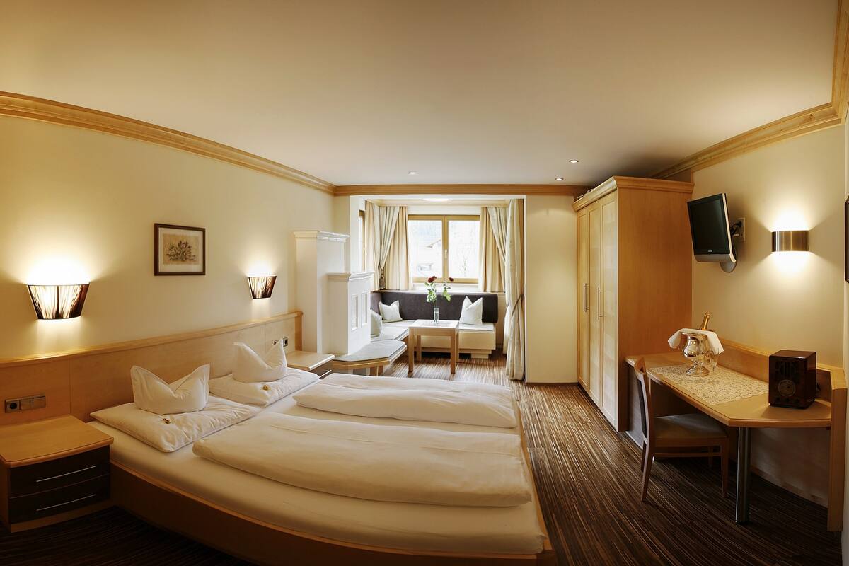 Een hotelkamer met twee bedden, een bureau, een stoel, een televisie en een raam met gordijnen.