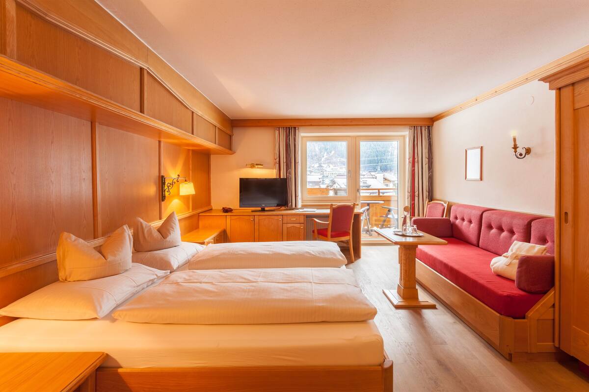 Een hotelkamer met twee bedden, een televisie, een bureau en een rode bank.