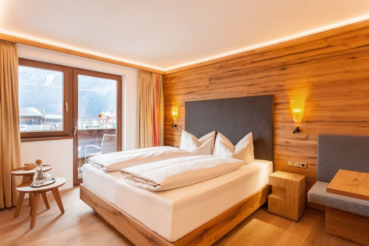 Een moderne hotelkamer met een houten hoofdeinde, een groot bed, nachtkastjes en uitzicht op de omgeving.