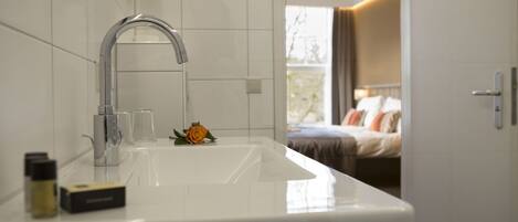 A modern bathroom with a white sink, a chrome faucet, and a small rose decoration.
