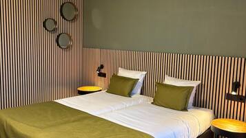 A hotel room with a large bed, two bedside tables, a wall-mounted TV, and a striped wall design.