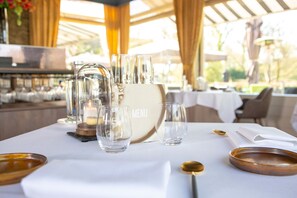 A table set for dining with a menu stand, clear glasses, and a candle. - Landgoed Hotel & Restaurant Carelshaven (Delden)