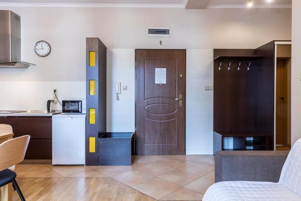 Una cocina compacta con microondas, un refrigerador pequeño y un armario de madera con detalles amarillos.