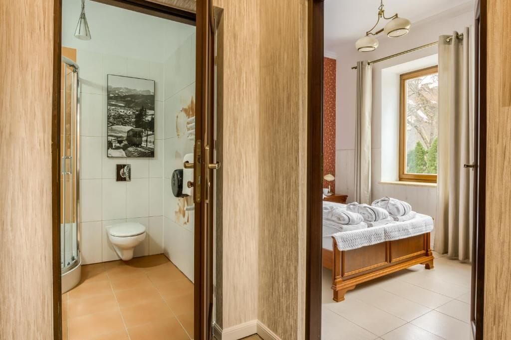 Un baño con inodoro, ducha y cama con toallas.