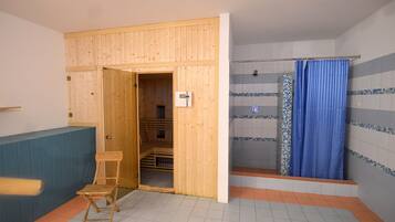 A room with a wooden sauna, a shower with blue curtains, and a blue bench.