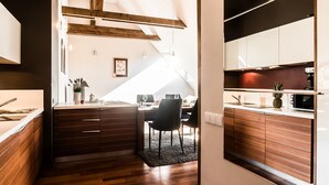 A modern kitchen with wooden cabinetry, a dining area with a table and chairs, and a view of the adjacent living space. - Tatrytop Apartamenty Radowid (Zakopane)
