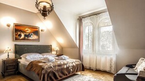 A bedroom with a bed, a nightstand, a lamp, a painting, and a window with curtains. - Tatrytop Apartamenty Radowid (Zakopane)
