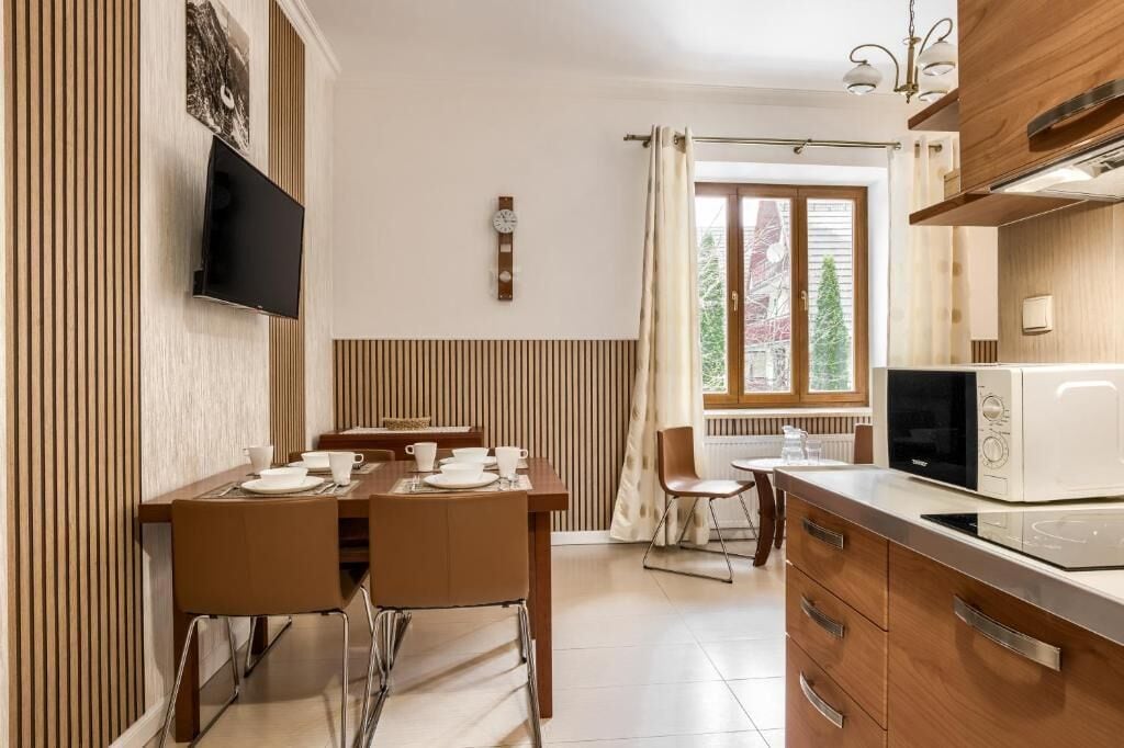 Una cocina moderna con comedor, televisor de pantalla plana, un reloj y una ventana con cortinas.