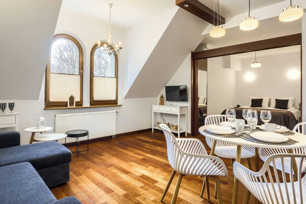 A modern room with a dining area, a sofa, a TV, and a large mirror.