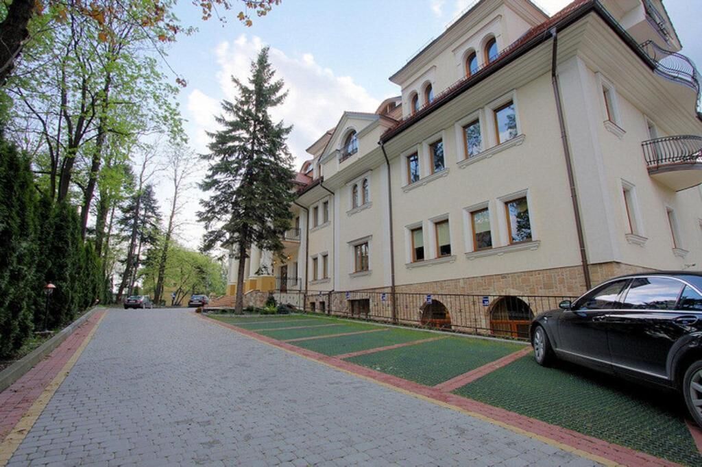 A multi-story building with a paved driveway and a green lawn area.