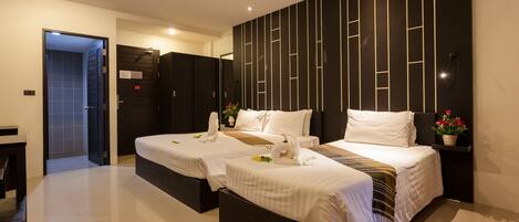 A modern hotel room with two beds, a dark accent wall, and a small potted plant.