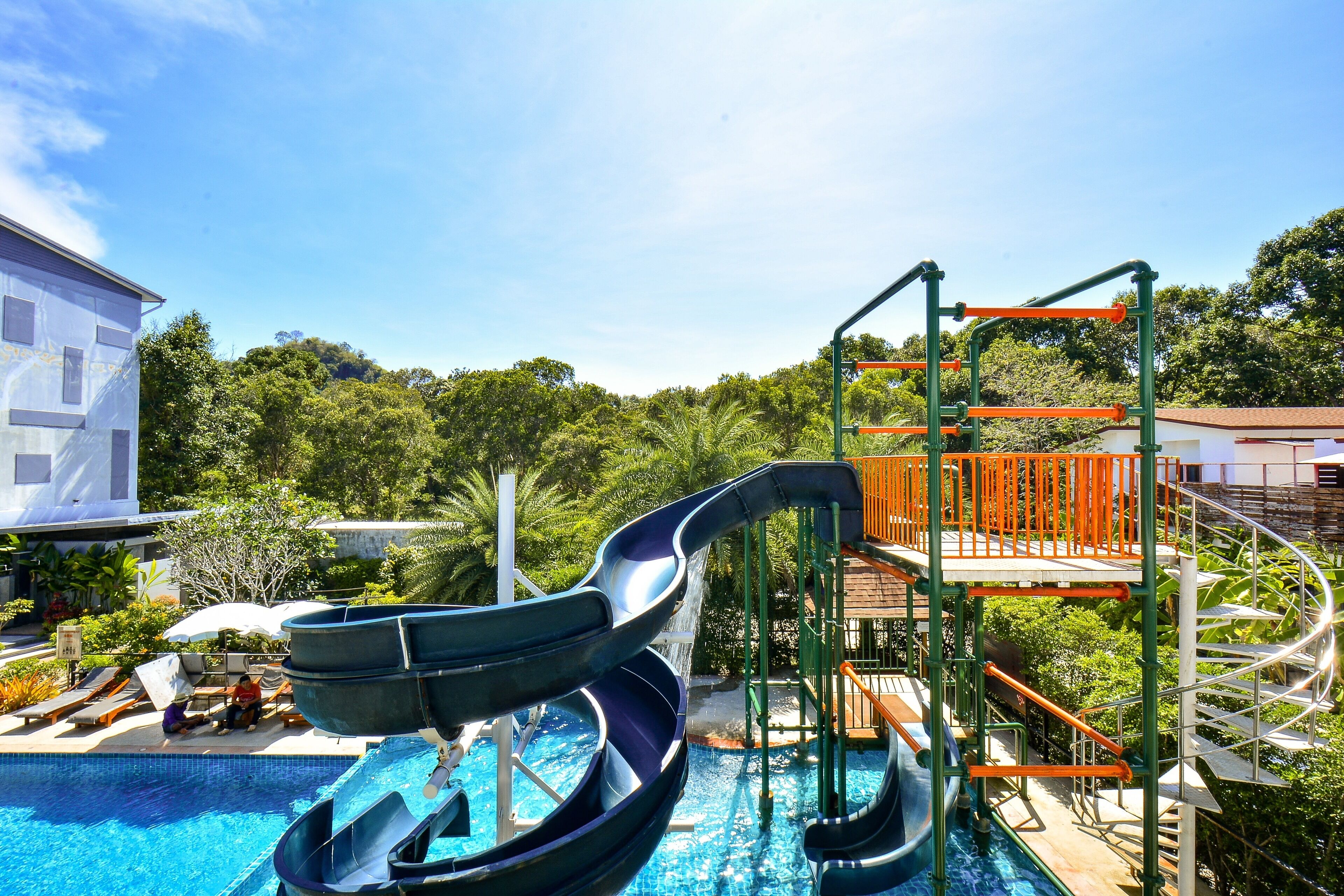 A swimming pool with two slides and a multi-level play structure.