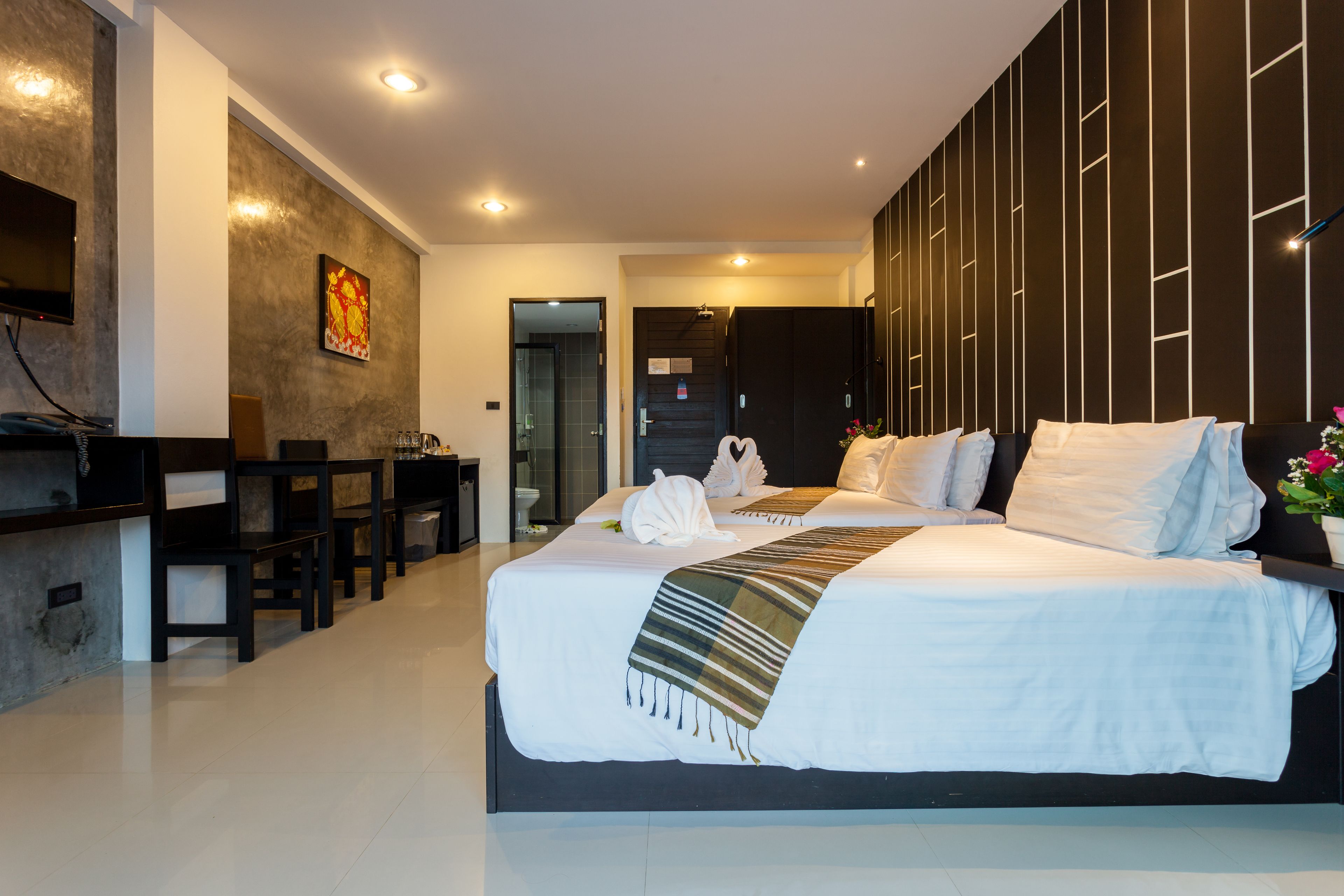 A modern hotel room with a large bed, a desk, and a TV.