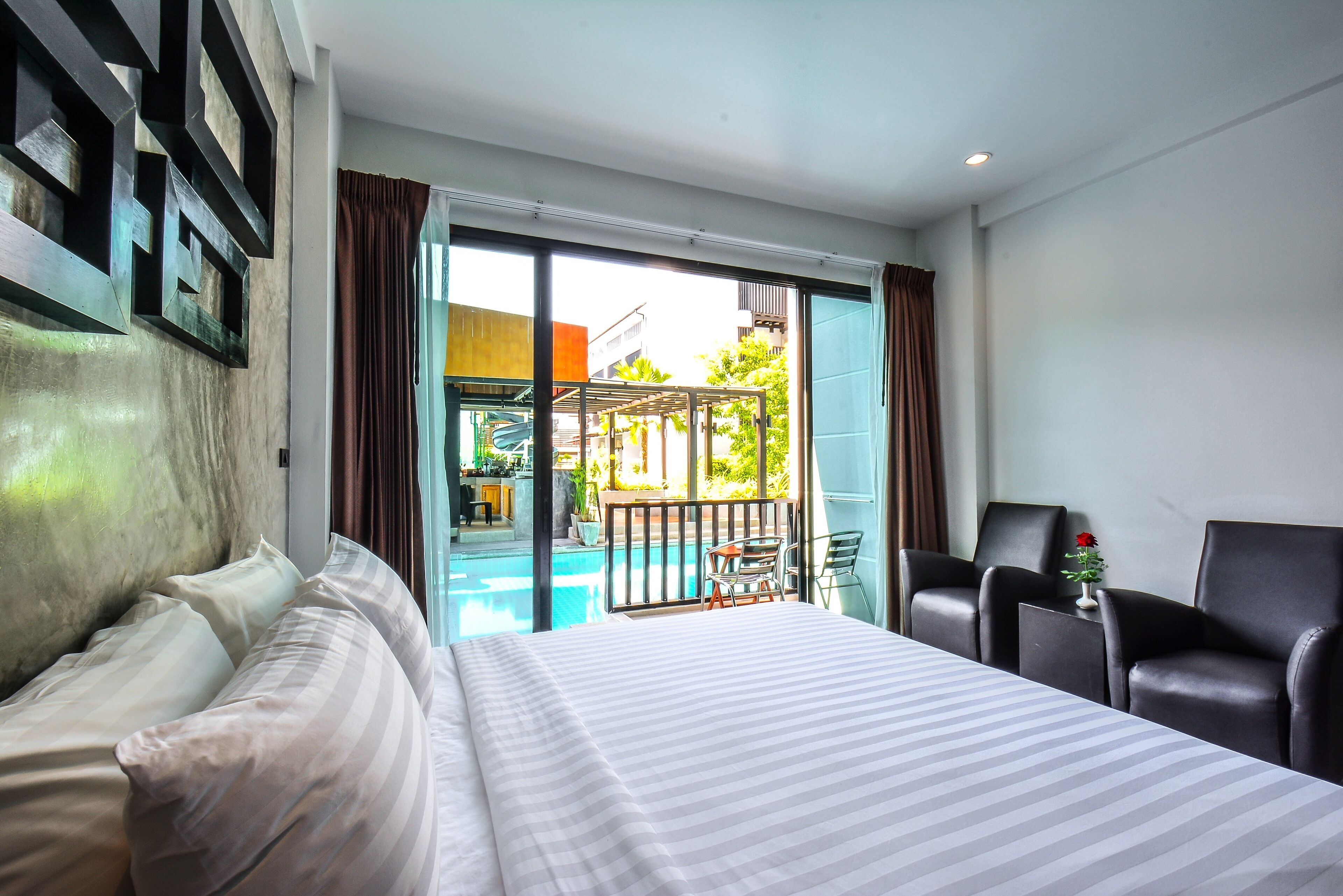 Habitación de hotel con una cama grande, un escritorio y vistas a una piscina y zona de estar al aire libre.