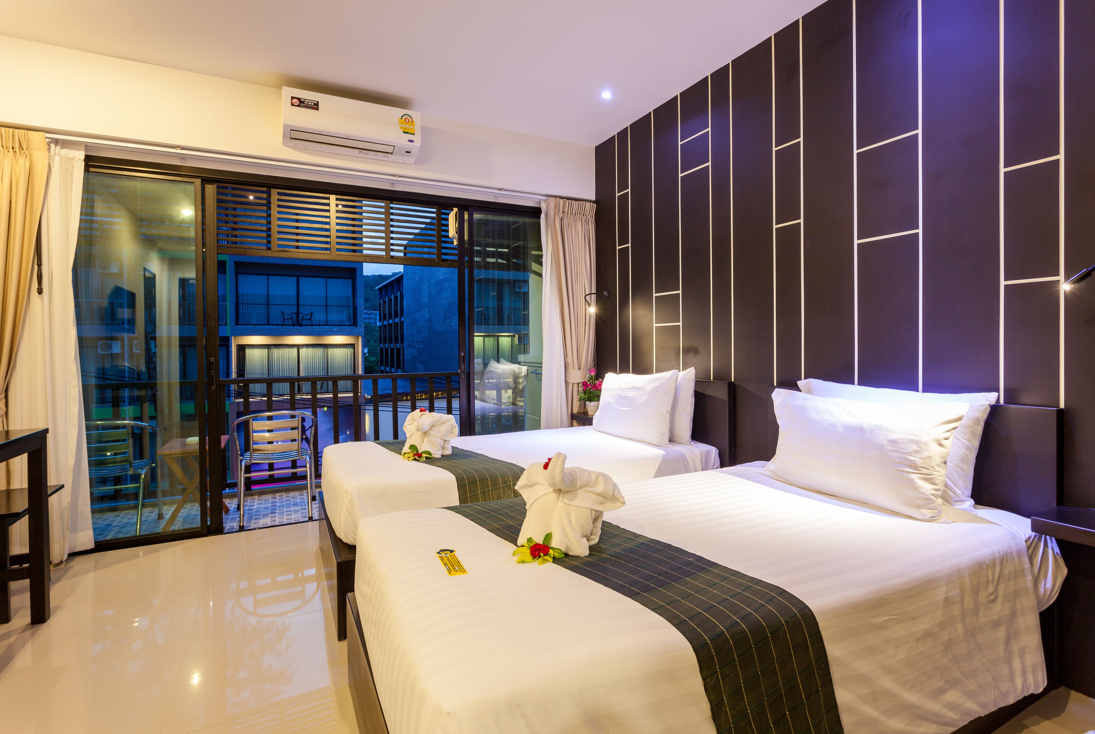 A hotel room with two beds, a balcony with a view, and a modern design.
