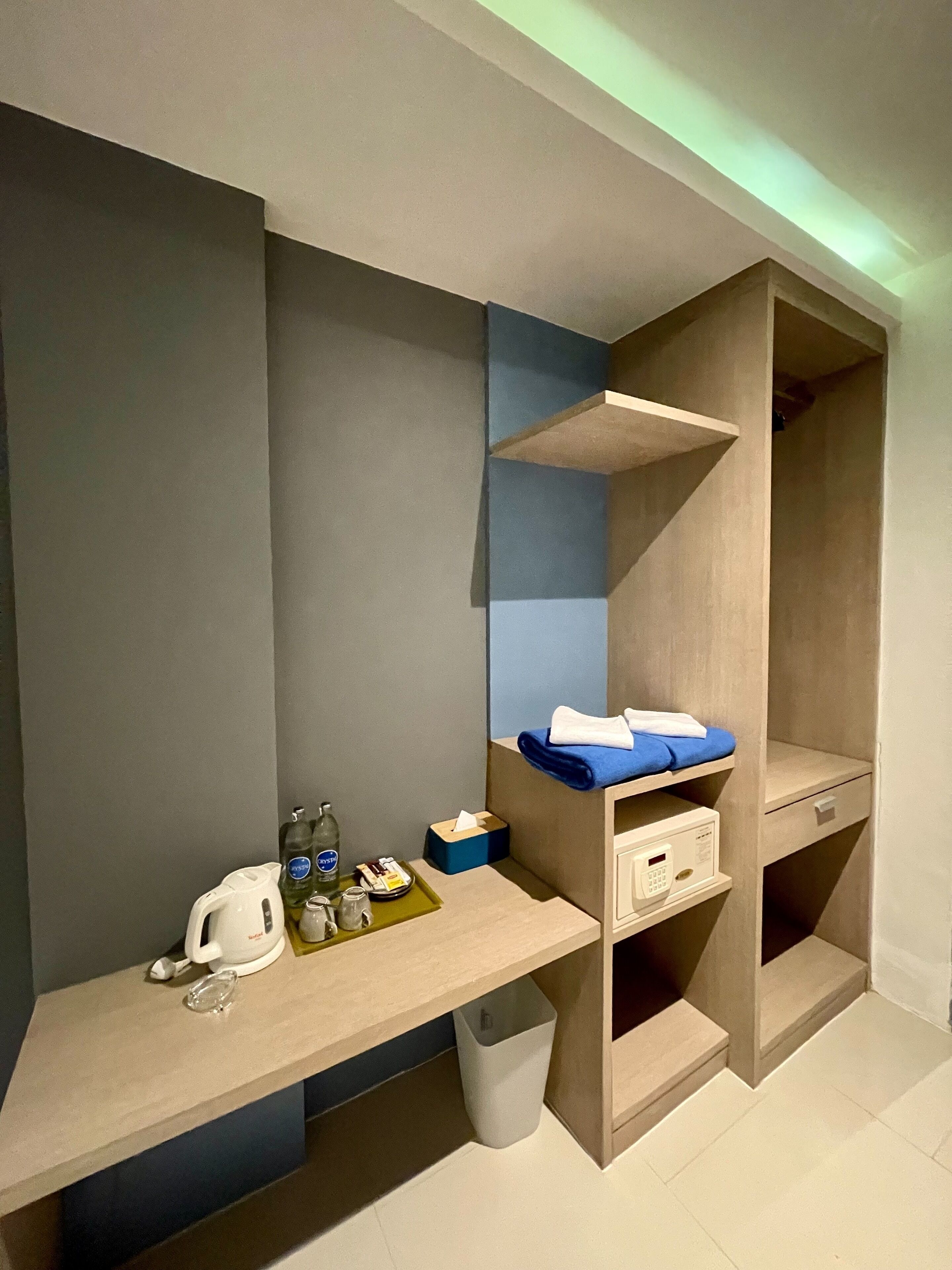 A modern, compact hotel room with built-in storage and a kitchenette area.