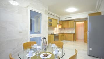 A modern kitchen with wooden cabinets, a glass dining table, and a refrigerator.