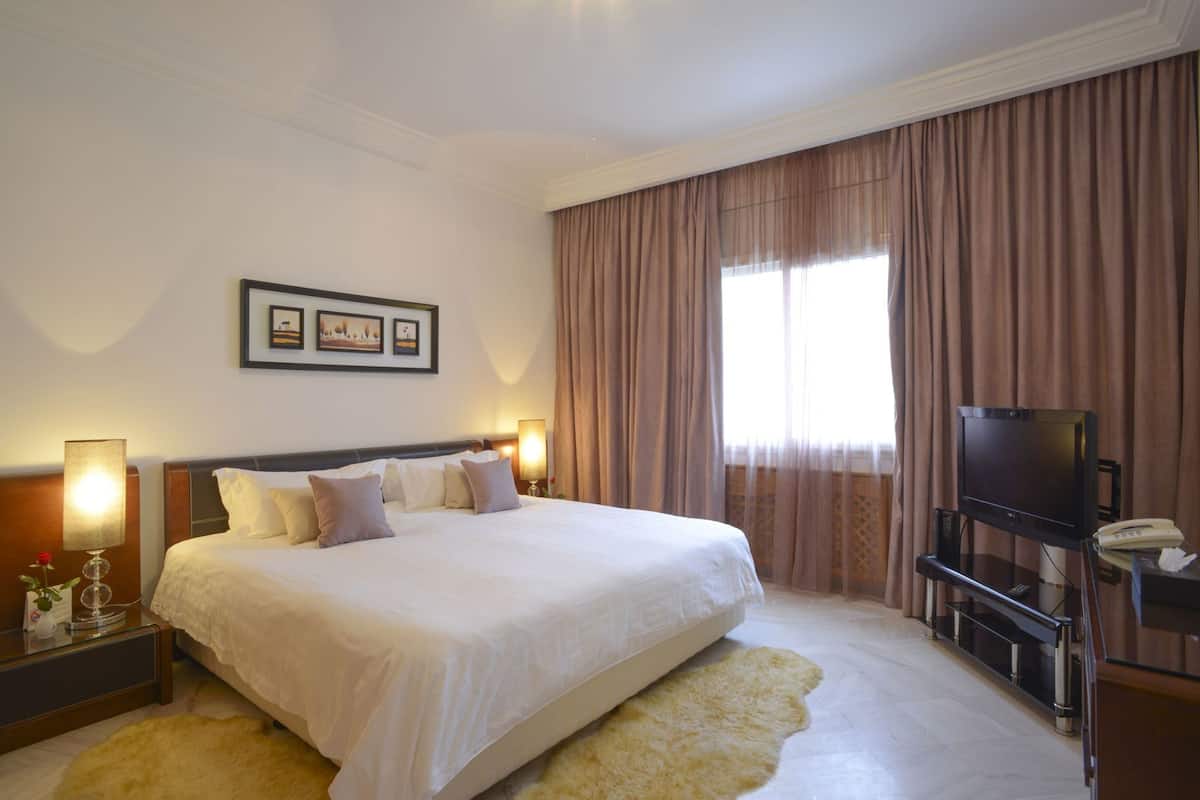 A hotel room with a large bed, a television, and a desk with a telephone.