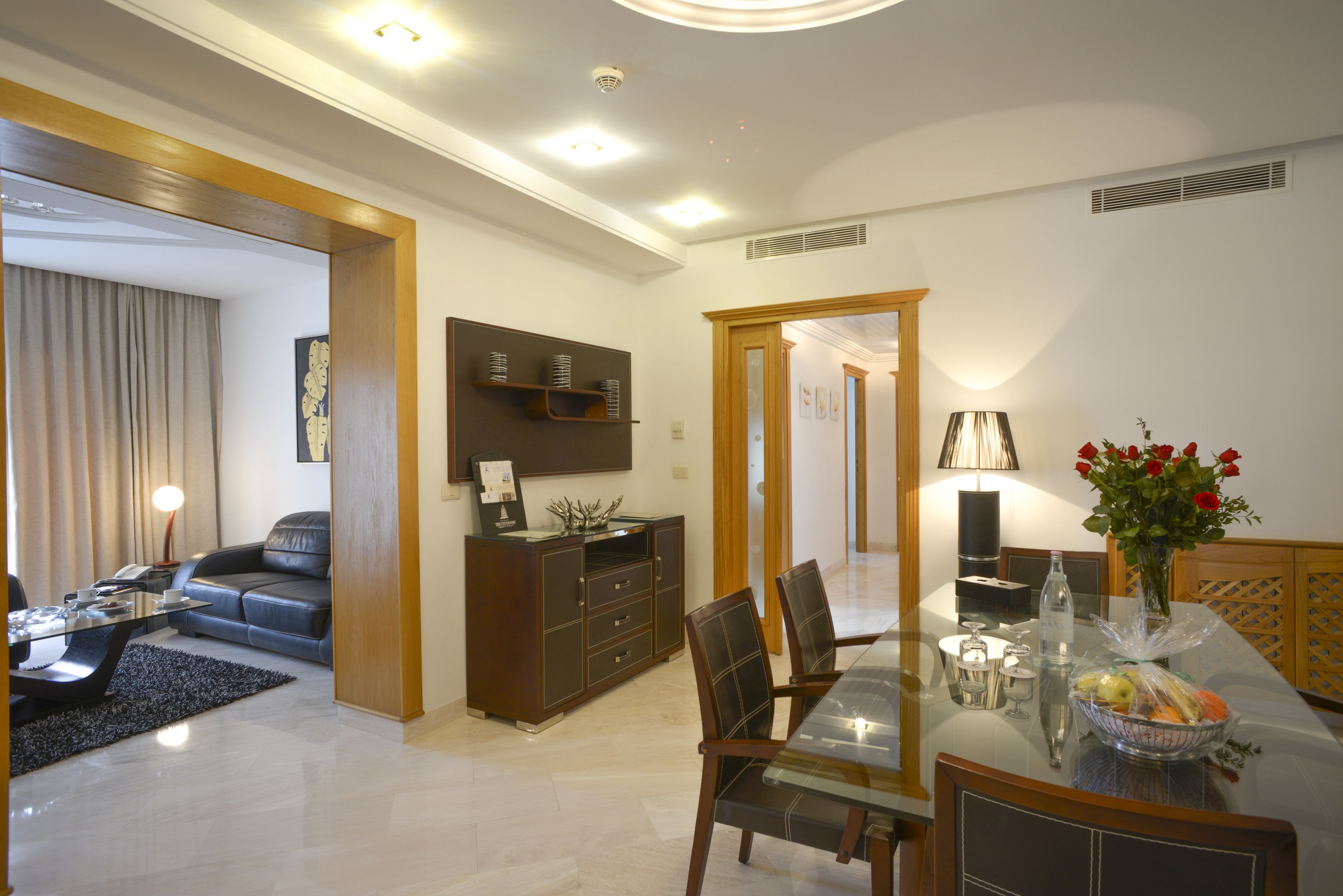A modern living room with a sofa, coffee table, and dining area with chairs and a table.