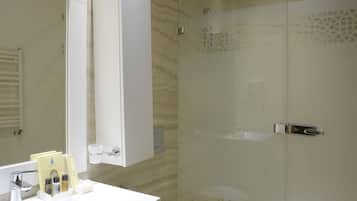 A modern bathroom with a glass-enclosed shower, a white sink with a mirror above it, and a toilet.