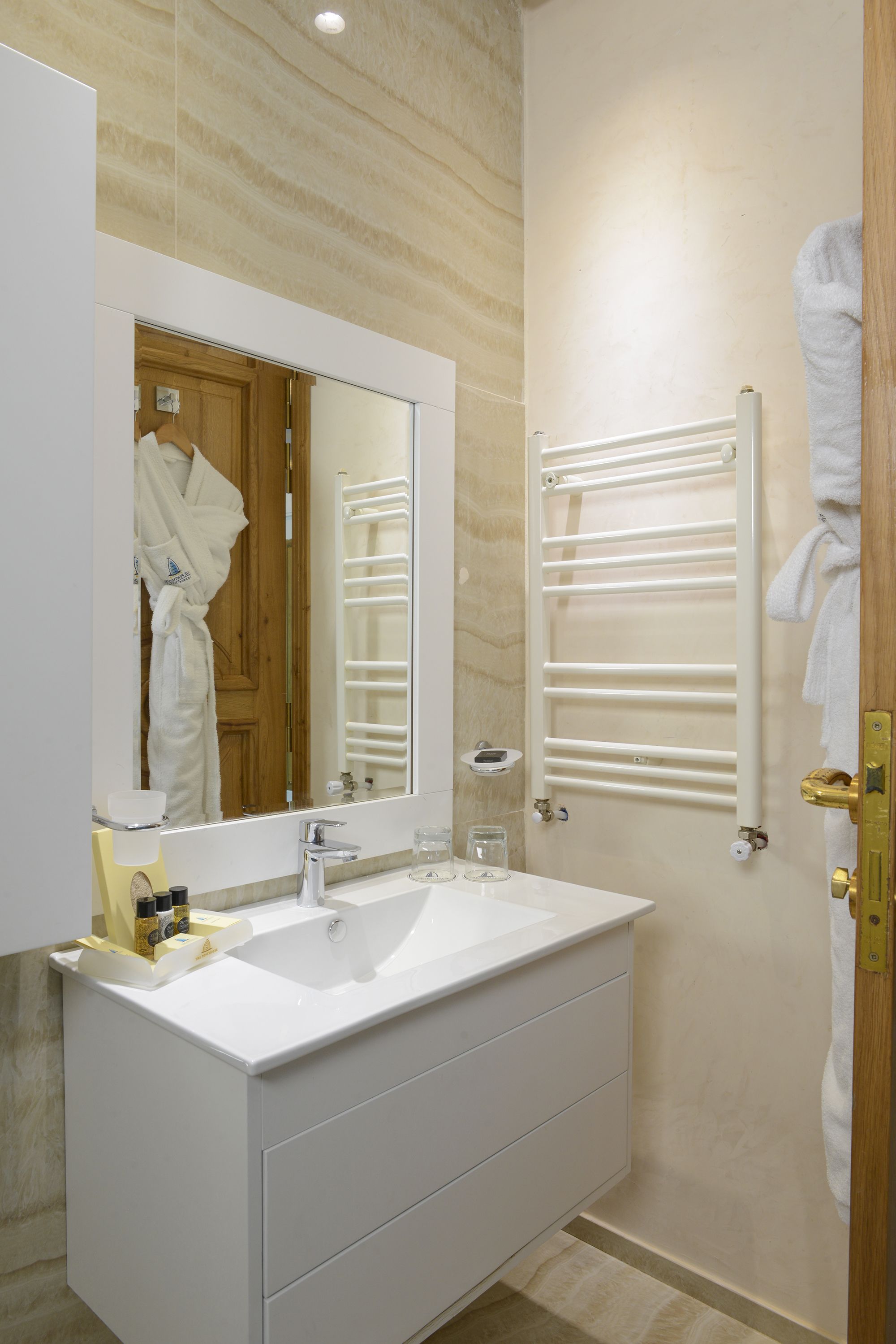 A modern bathroom with a large mirror, white sink, and towel rack.
