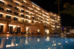 A hotel with multiple floors, outdoor pool, and lounge area with chairs and umbrellas. - Melini Hotel Suites (Paralimni)