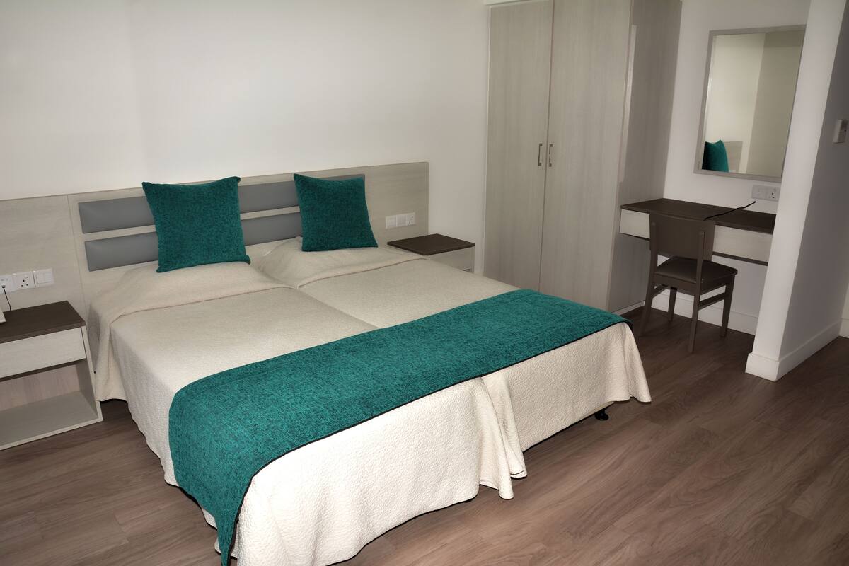 Une chambre à coucher comprenant un lit, deux tables de chevet, un bureau et une armoire.