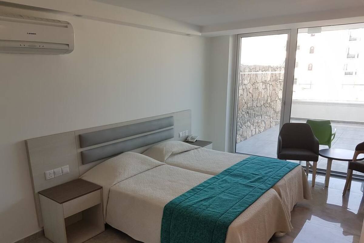 Une chambre d’hôtel avec un lit, une table de chevet et une vue sur le balcon extérieur.