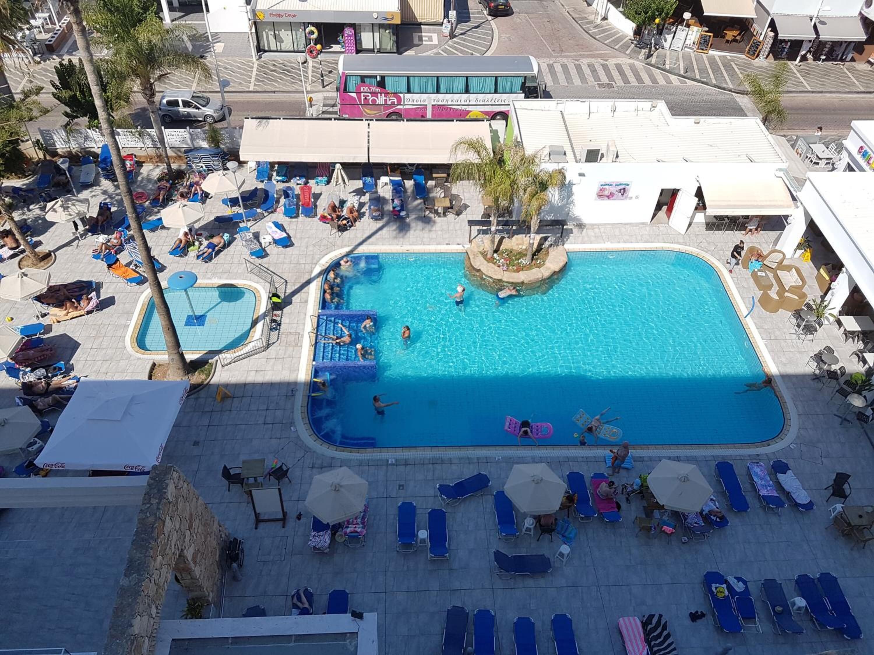 Un espace piscine aménagé sur le toit, comprenant plusieurs piscines, des chaises longues et des parasols.