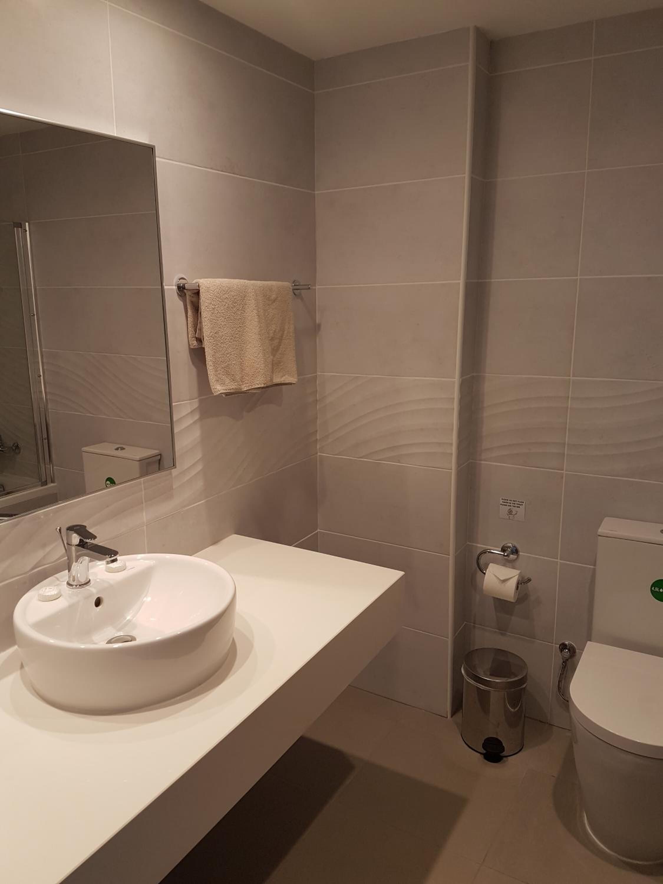 Un baño moderno con un lavamanos, espejo y retrete blancos.