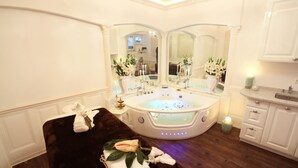 Ein luxuriöses Badezimmer mit einer großen Badewanne, einem Doppelwaschbecken inklusive Spiegeln und einer dunkelbraunen Badematte.