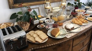 A buffet table with various food items, including bread, pastries, and a pie, along with tea and juice. - Agriturismo Campanacci (Faenza)