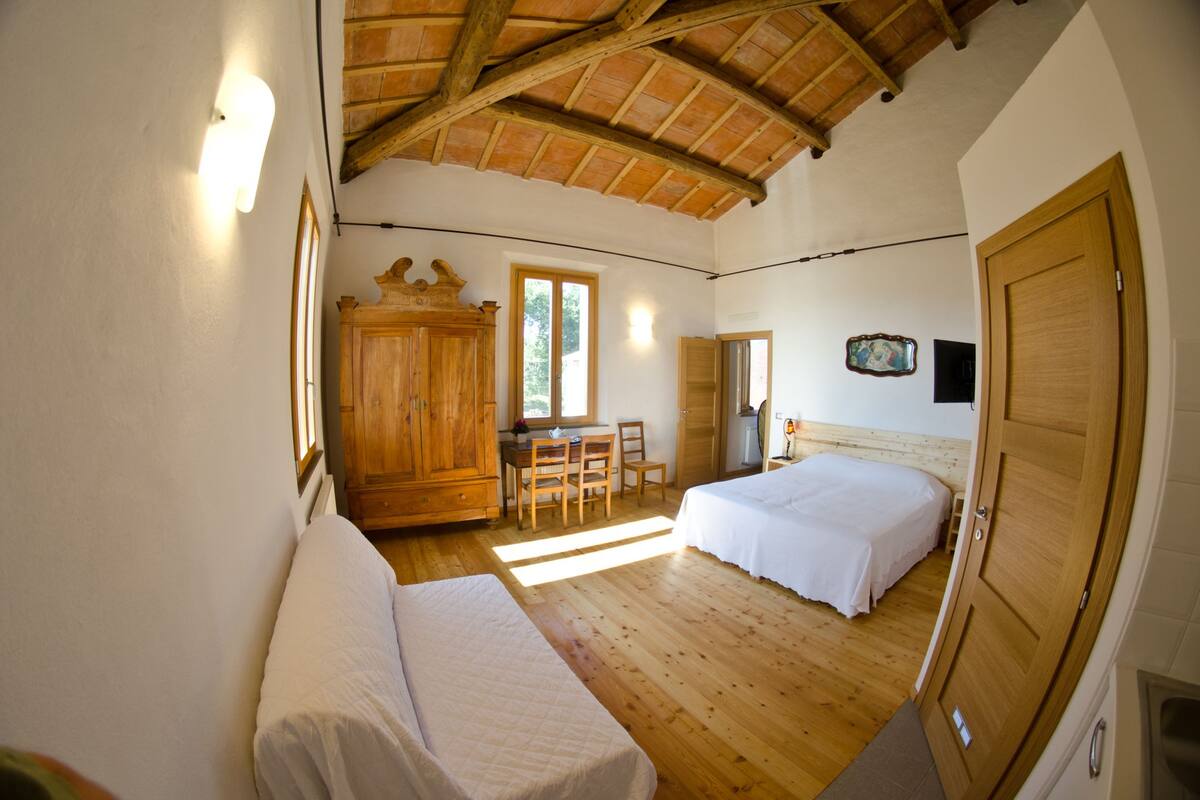 A bedroom with a wooden ceiling, a bed, a desk, and a wardrobe.