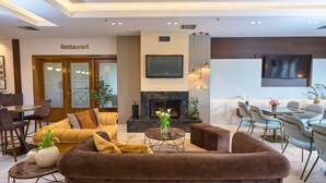 A modern living area with a fireplace, comfortable seating, and a dining area. - Hotel Filippos (Chalkidona)