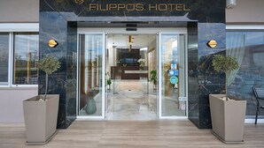 The entrance to the Filippos Hotel with a marble facade, glass doors, and two potted plants. - Hotel Filippos (Chalkidona)