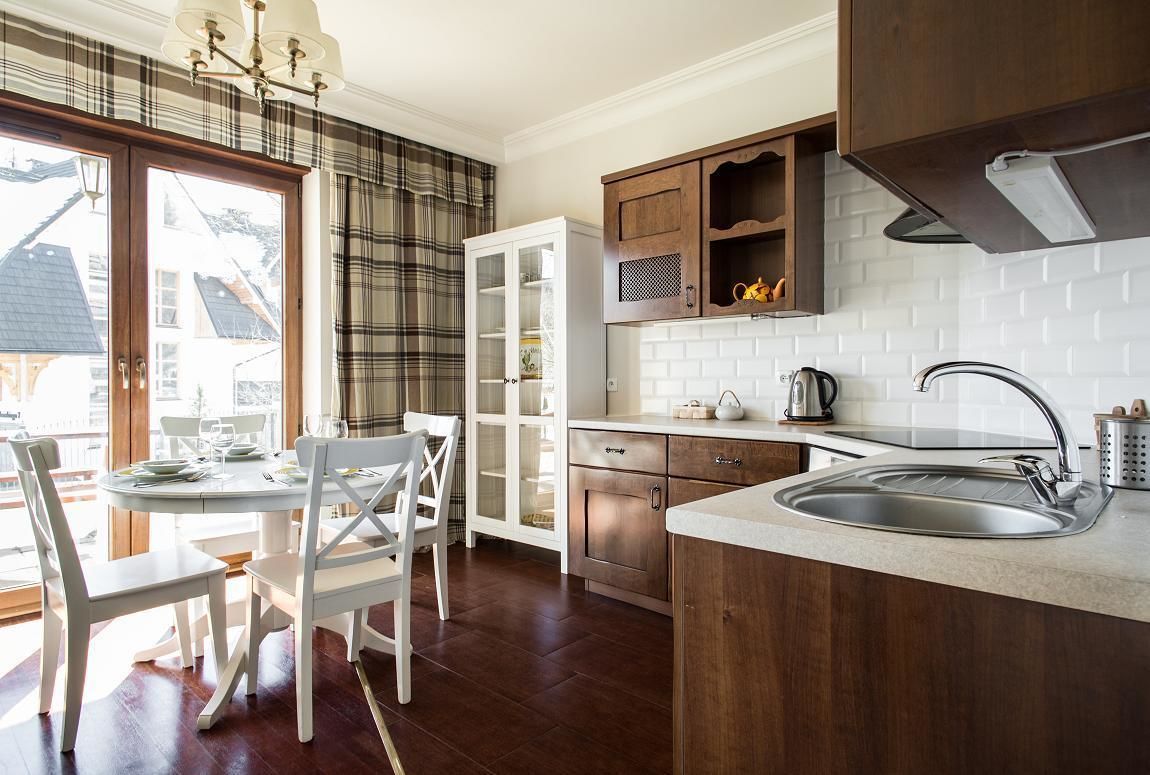 A kitchen with a white countertop, stainless steel sink, and wooden cabinets.