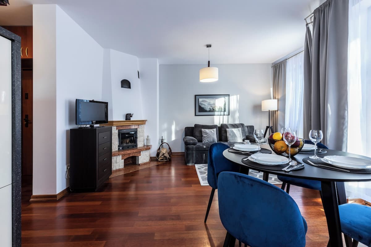 Una sala de estar moderna con chimenea, un comedor con mesa dispuesta para dos, y un sofá.
