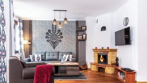 Una sala de estar con un sofá, una chimenea, un televisor y un adorno en la pared.