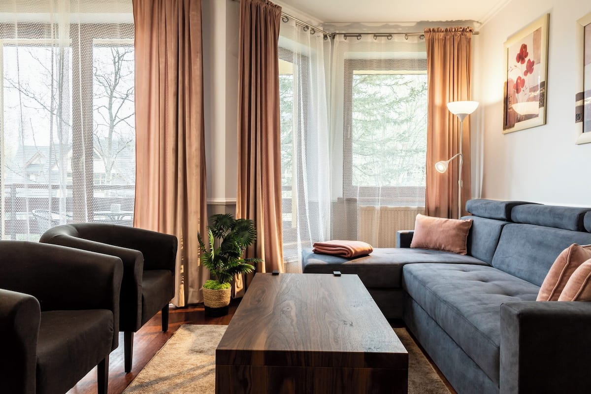 Una sala de estar moderna con un sofá, sillones, una mesita de centro y una planta en maceta.