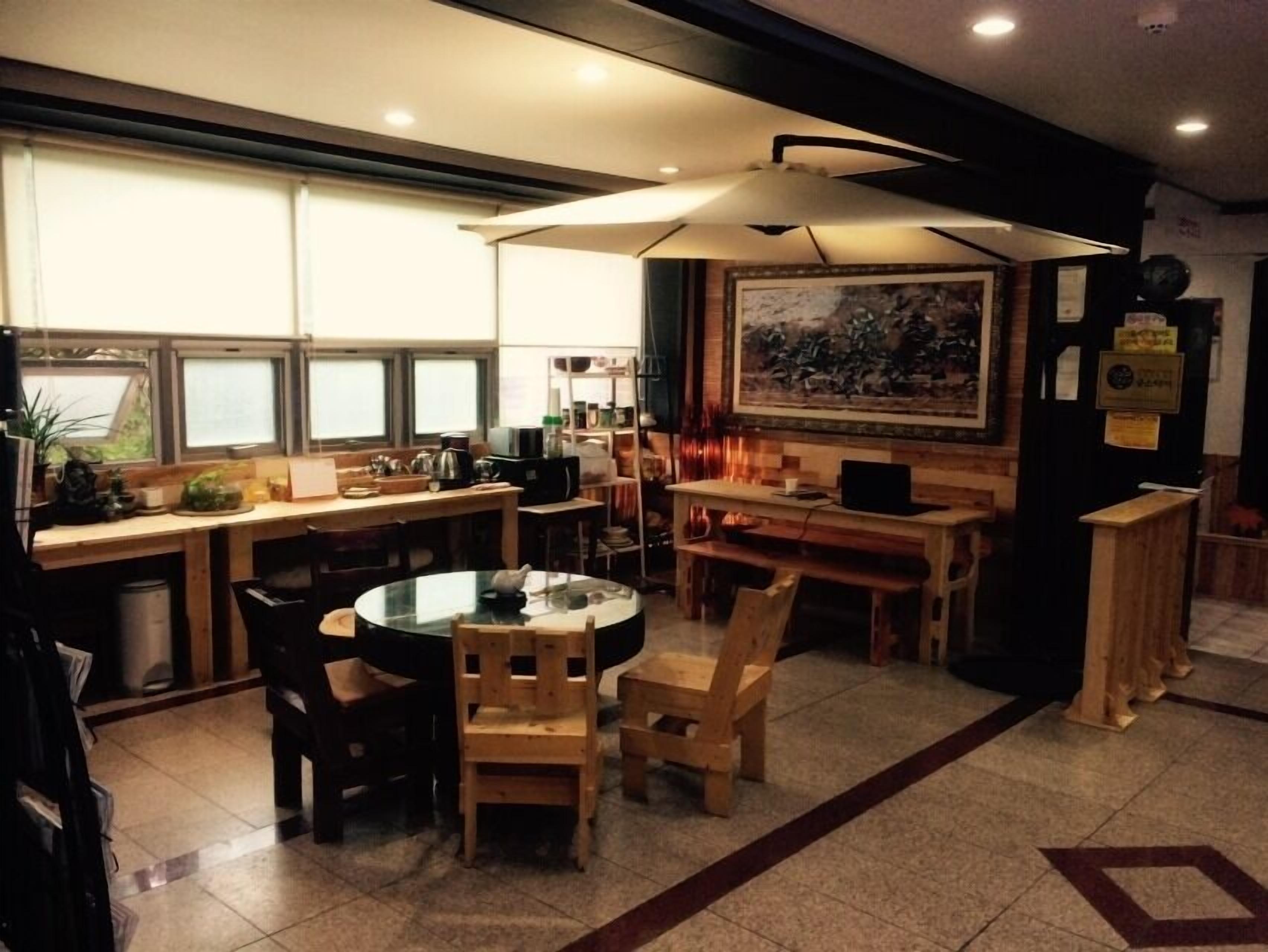 A cozy restaurant with a round table, wooden chairs, and a large painting on the wall.