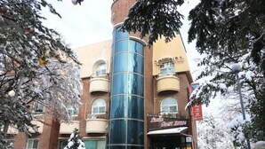 A multi-story building with a prominent cylindrical glass tower, a sign reading "Smile Guest House," and a snow-covered environment.